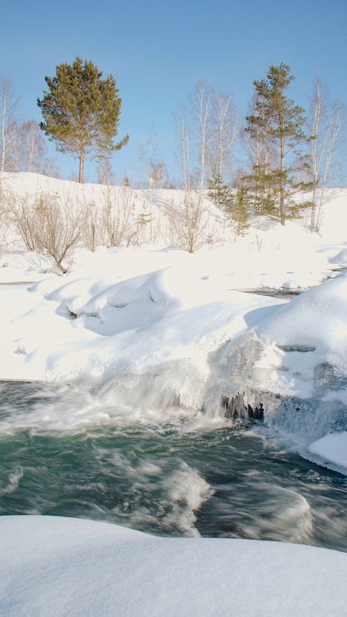 Free A Stream and a Snow Covered Landscape Stock Photo