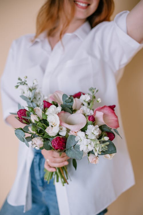 Woman in White Shirt Holding Bouquet of Flowers