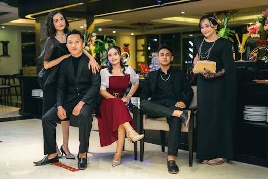 Stylish group of young adults in formal attire posing indoors at a classy event.