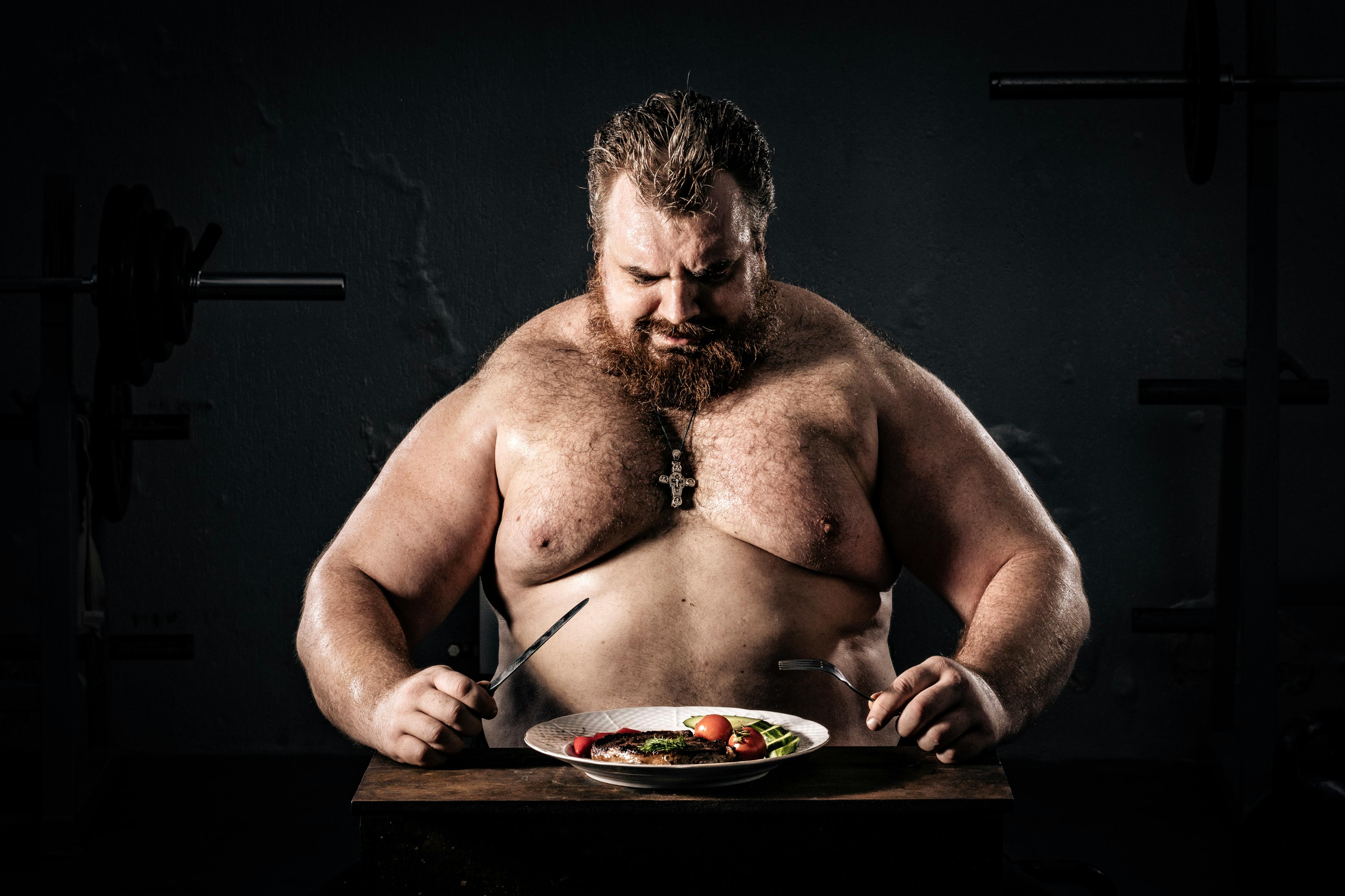 Shirtless muscular man eating a nutritious meal, symbolizing strength and health.