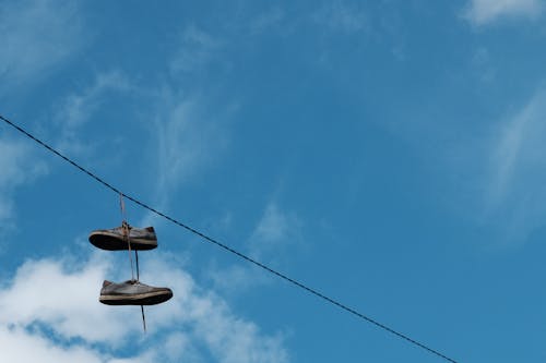 Free Brown Shoes Hanging on Black Cable Wire Under Blue Sky Stock Photo