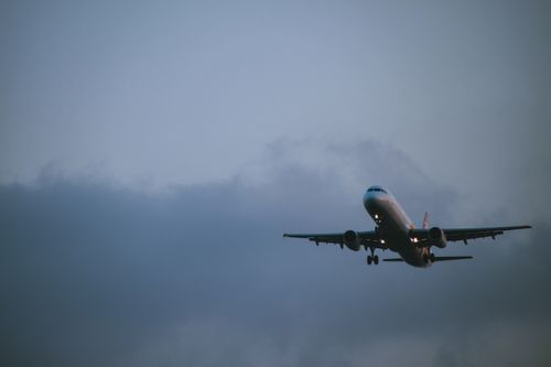 Free A commercial airplane flying against a cloudy sky during twilight. Perfect for travel and aviation themes. Stock Photo