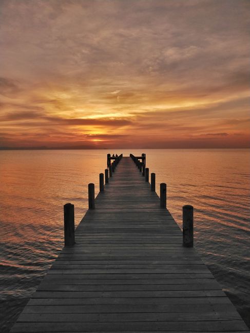 A breathtaking sunset view over a wooden jetty in Kampot Province, Cambodia.