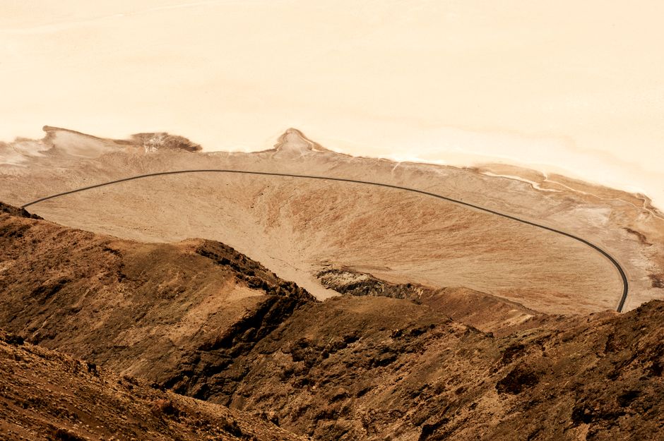 High angle view of a rugged desert landscape in Death Valley, showcasing a winding road.