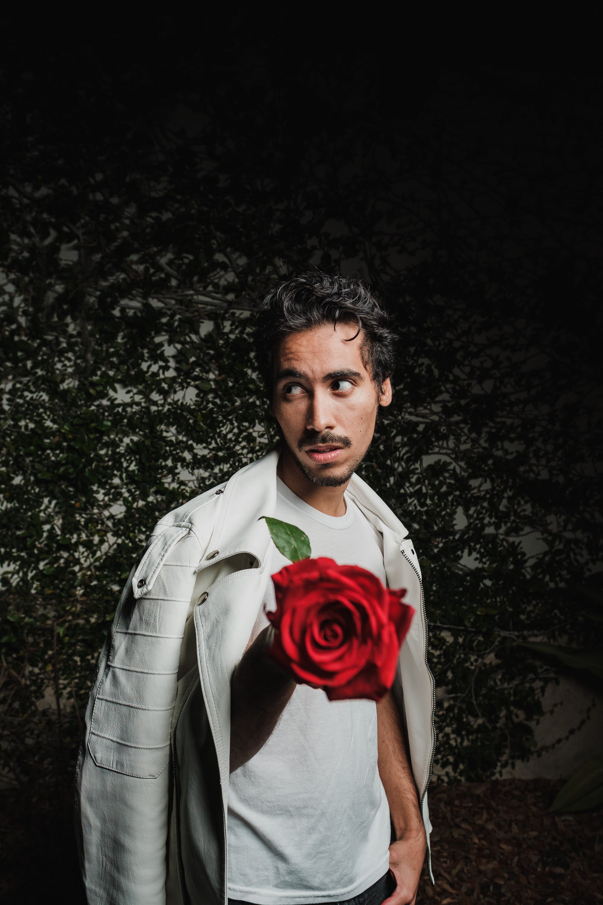 man in white jacket holding a rose