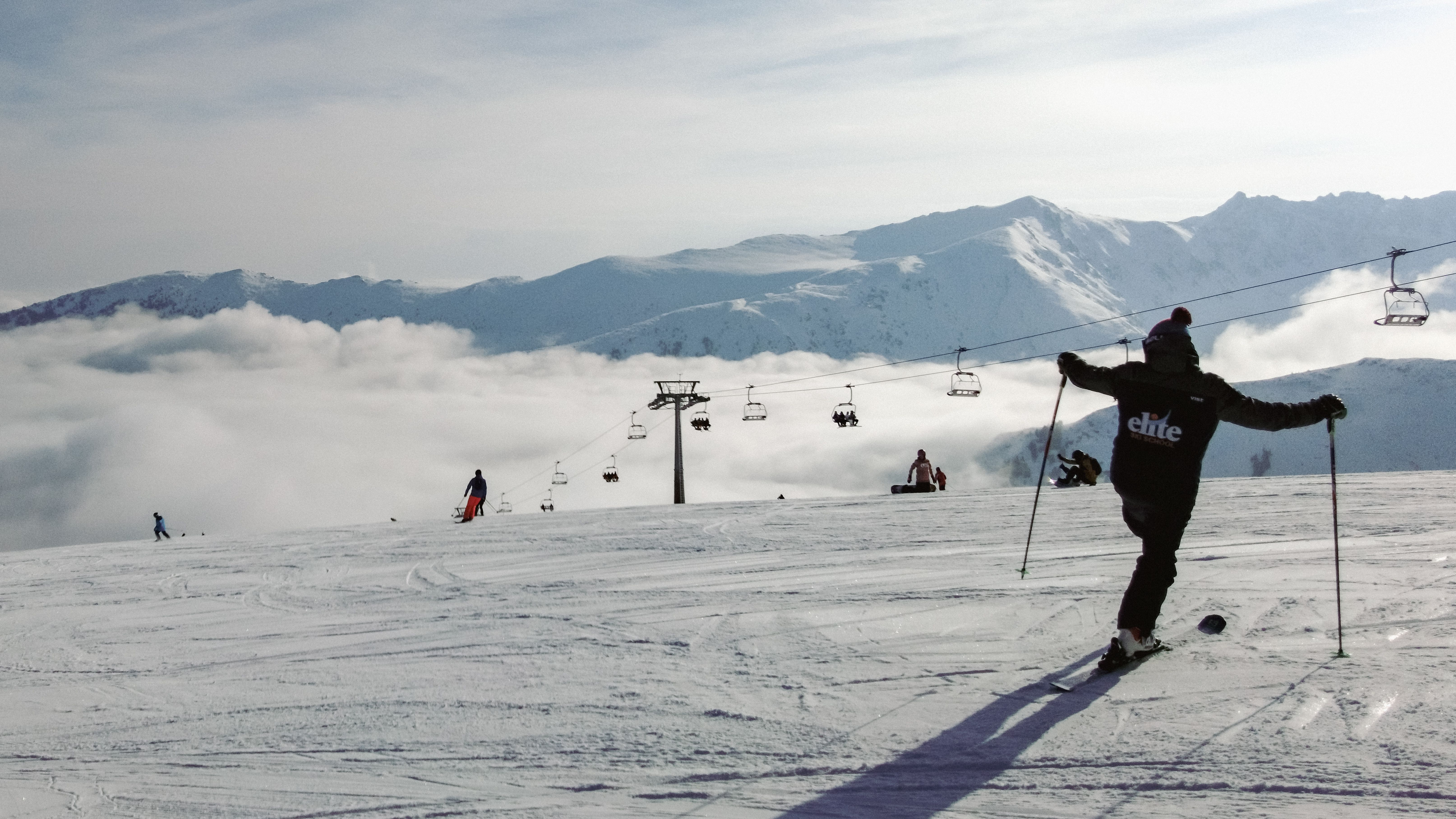 Skiers enjoying a peaceful day on snow-covered mountains with scenic views and a clear sky.
