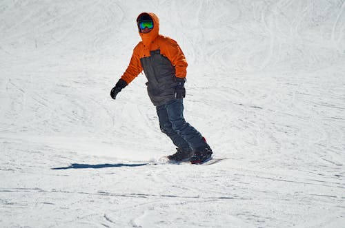 Free Man in Orange Jacket Snowboarding on Thick Snow  Stock Photo