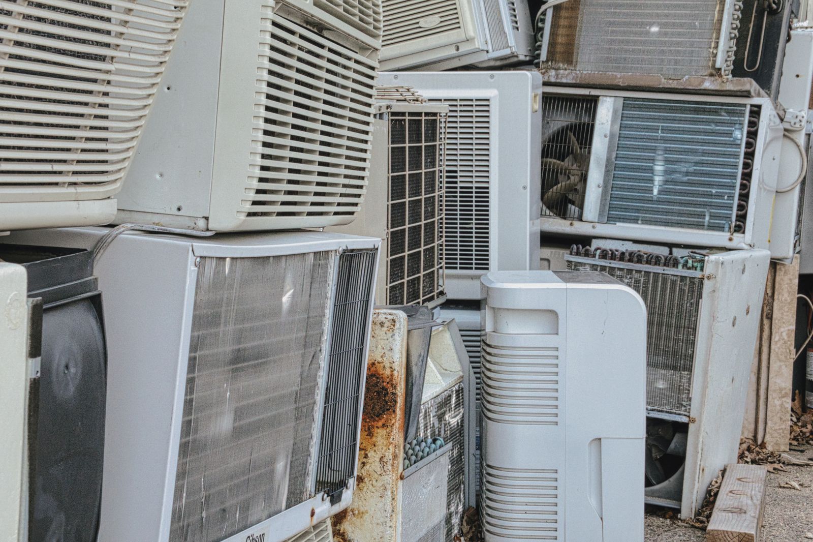 A messy, cluttered pile of old, discarded air conditioning units stacked outdoors. — Bethel Heating Services: why we answer the phone 24/7 in Bethel — Bethel Heating Services, Bethel