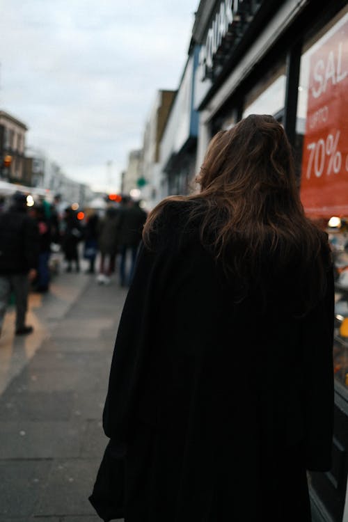 Back View of a Woman in Black Coat Walking on Sidewalk