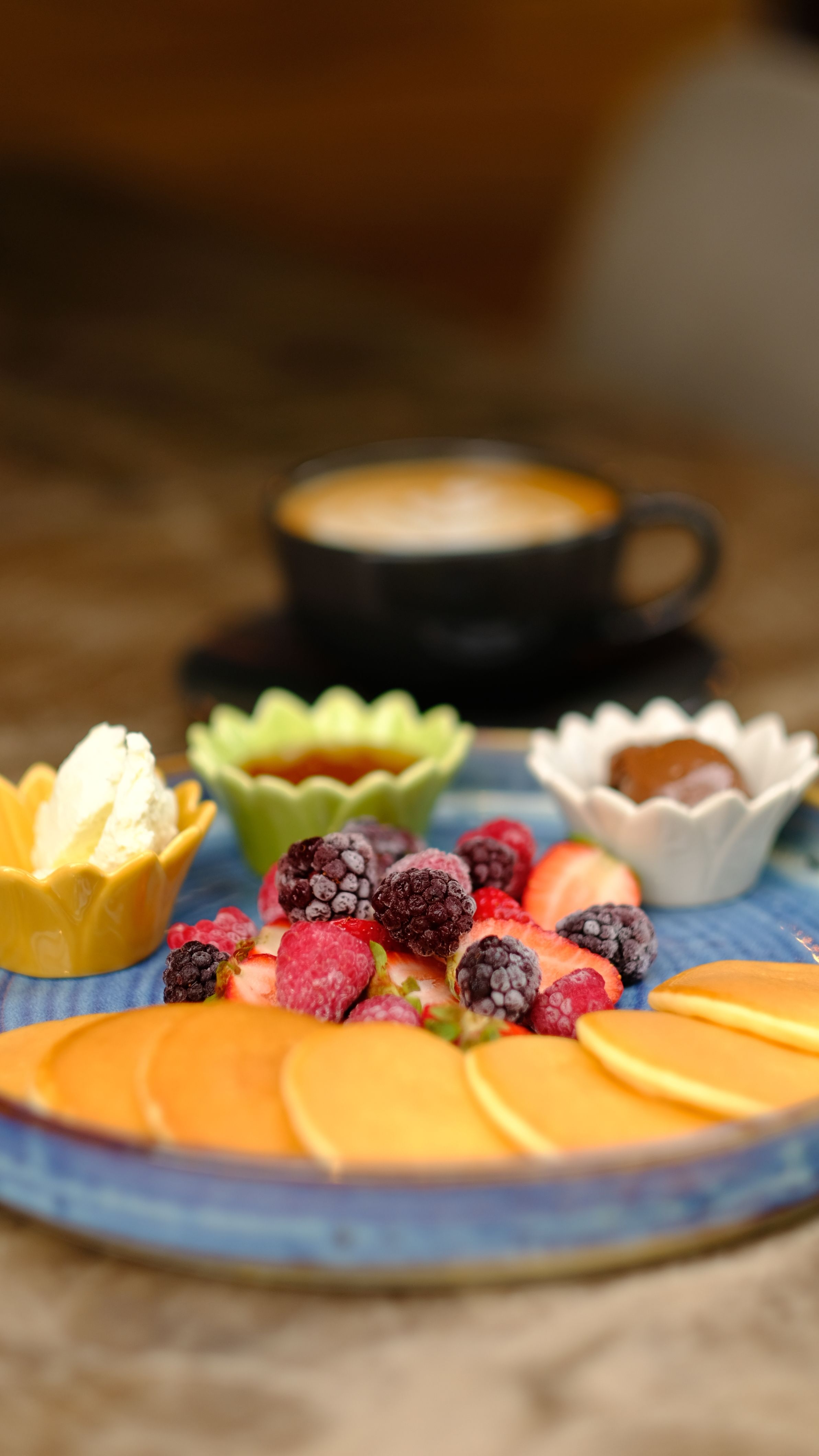 Colorful fruit platter with berries and mango slices, served with a cup of coffee. Perfect for breakfast settings.