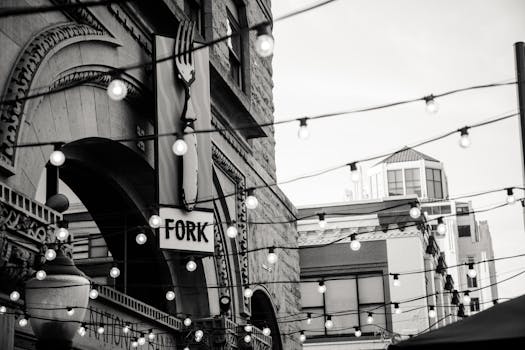 Architectural facade with decorative string lights and a 'Fork' restaurant sign in urban setting.