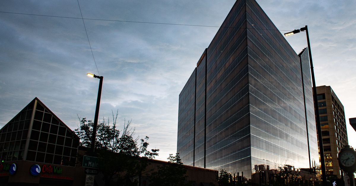 Capture of a sleek, modern skyscraper against a twilight sky in a bustling urban setting.