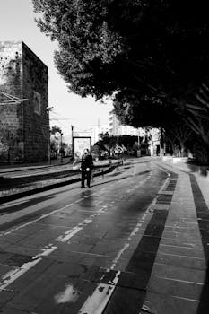 Black and white photo of a solitary figure walking down an urban street.