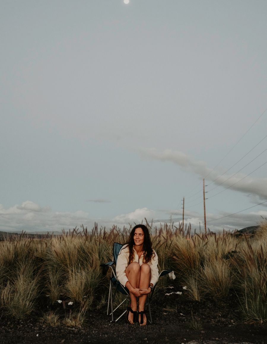 A woman sitting on a chair in an open grassy field — photo by Daniel Torobekov on Pexels