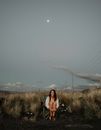 Woman in Black Tank Top Standing on Green Grass Field Under Gray Sky