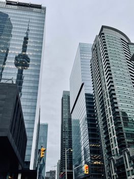 Low angle shot of skyscrapers with CN Tower reflection in Toronto's financial district.