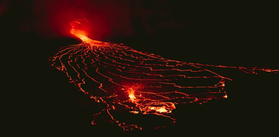 Photo by Daniel Torobekov A stunning capture of a volcanic eruption with flowing lava under the night sky.