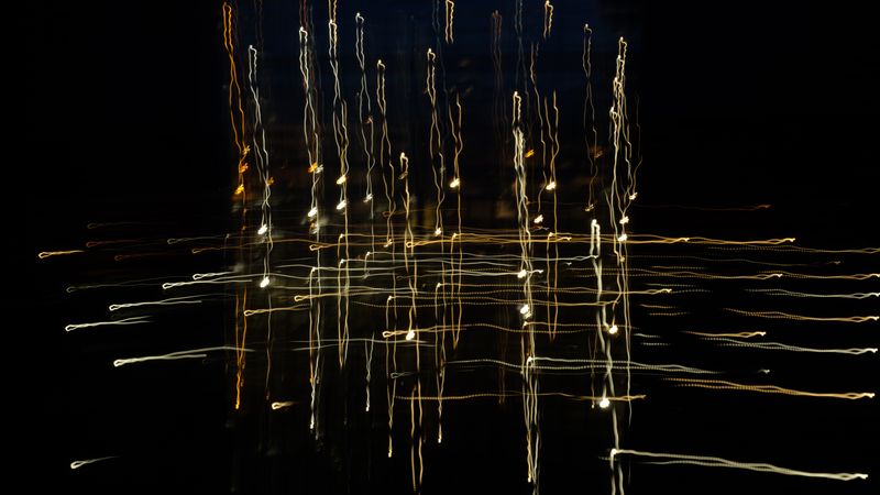 Long-exposure filaments of light branching over dark water, by Ludvig Hedenborg on Pexels