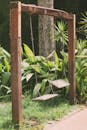 Swings on Wooden Posts Near Green Plants