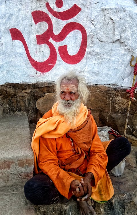 Free An Elderly Man in Orange Long Sleeves Sitting on the Street Stock Photo