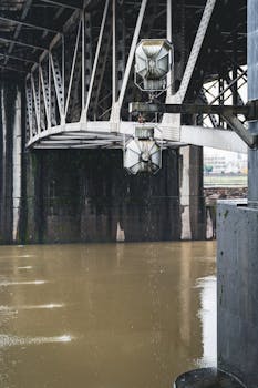 Close-up of a steel bridge structure over a murky canal, showcasing detailed metal construction.