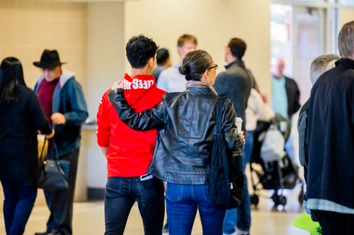 Free Mother and son walk with arm around each other in a busy indoor setting. Stock Photo