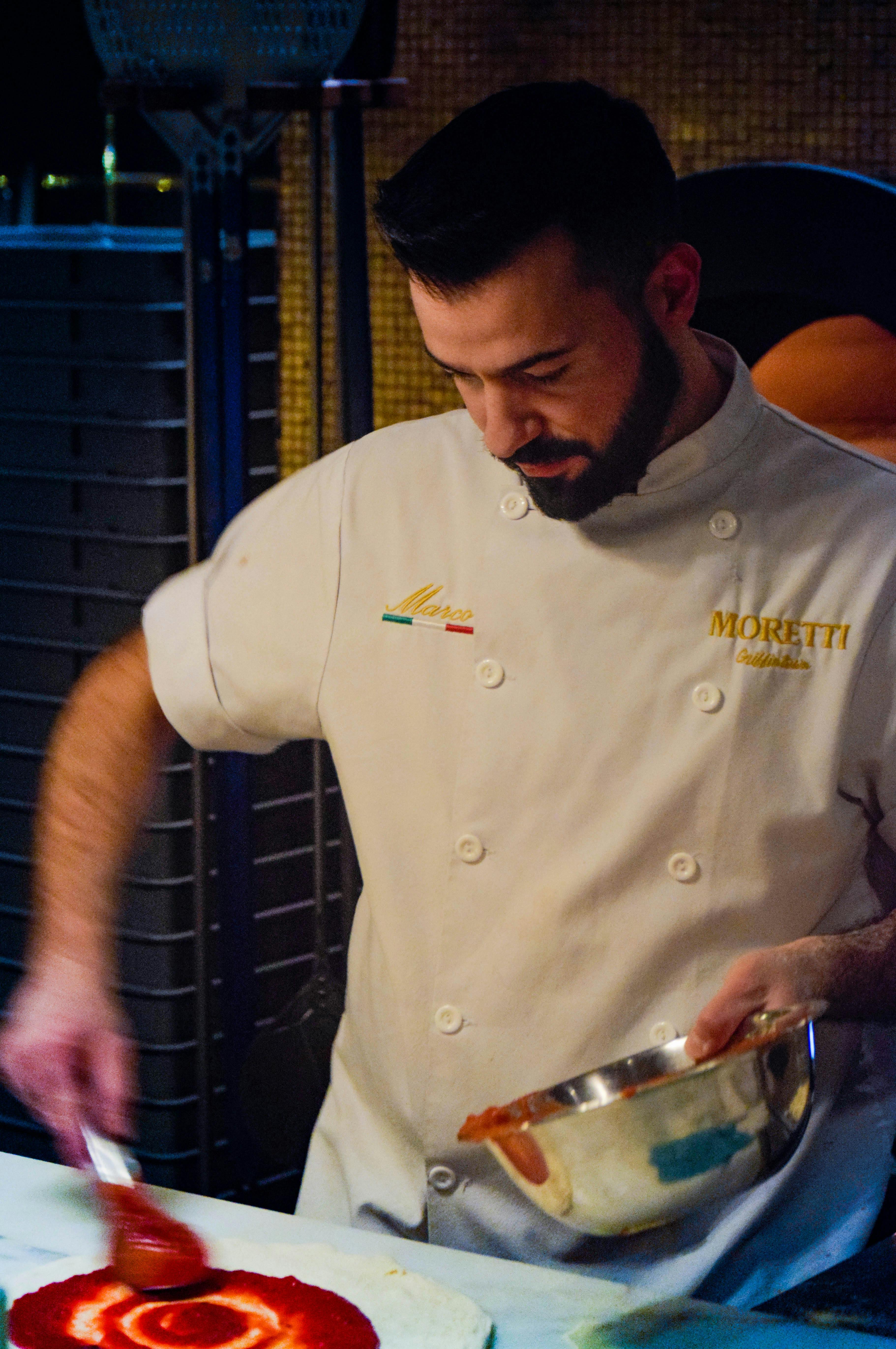 Bearded chef prepares a gourmet pizza in a Toronto kitchen.