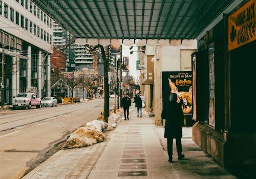 Urban winter scene in Toronto with people walking along a snowy sidewalk in the city.