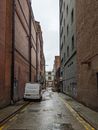 A White Van Parked on the Street Between Brick Buildings