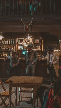 Three cowboys stand at a rustic saloon bar, capturing classic western ambiance.