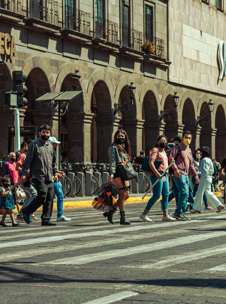 A Group Of People Walking On Pedestrian Lane While Wearing Face Masks