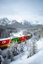 Red and Green Train on Snow Covered Ground Near Snow Covered Mountain