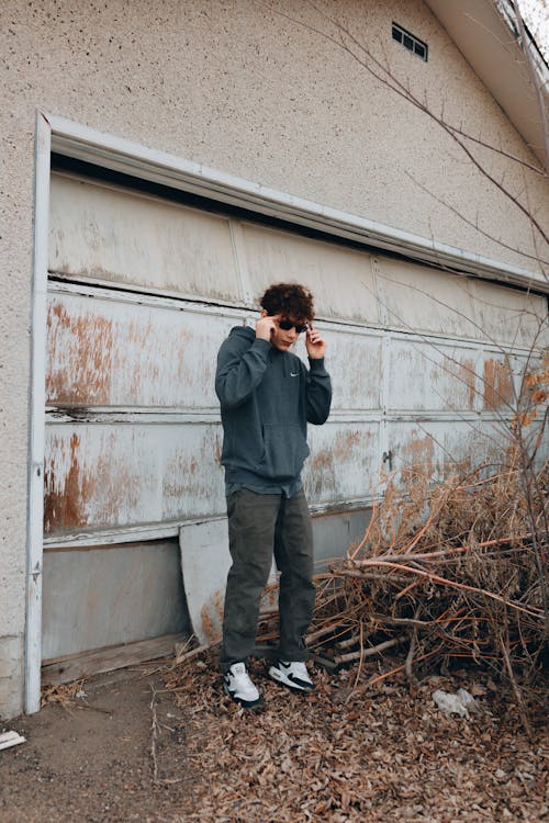 A Man in Gray Sweater Standing Near the Abandoned House