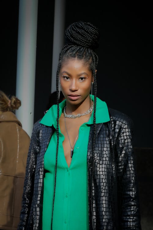 A Woman in Green Shirt and Black Leather Coat Looking with a Serious Face