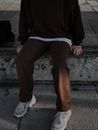 A Person in Black Sweater and Brown Pants Sitting on a Concrete Step