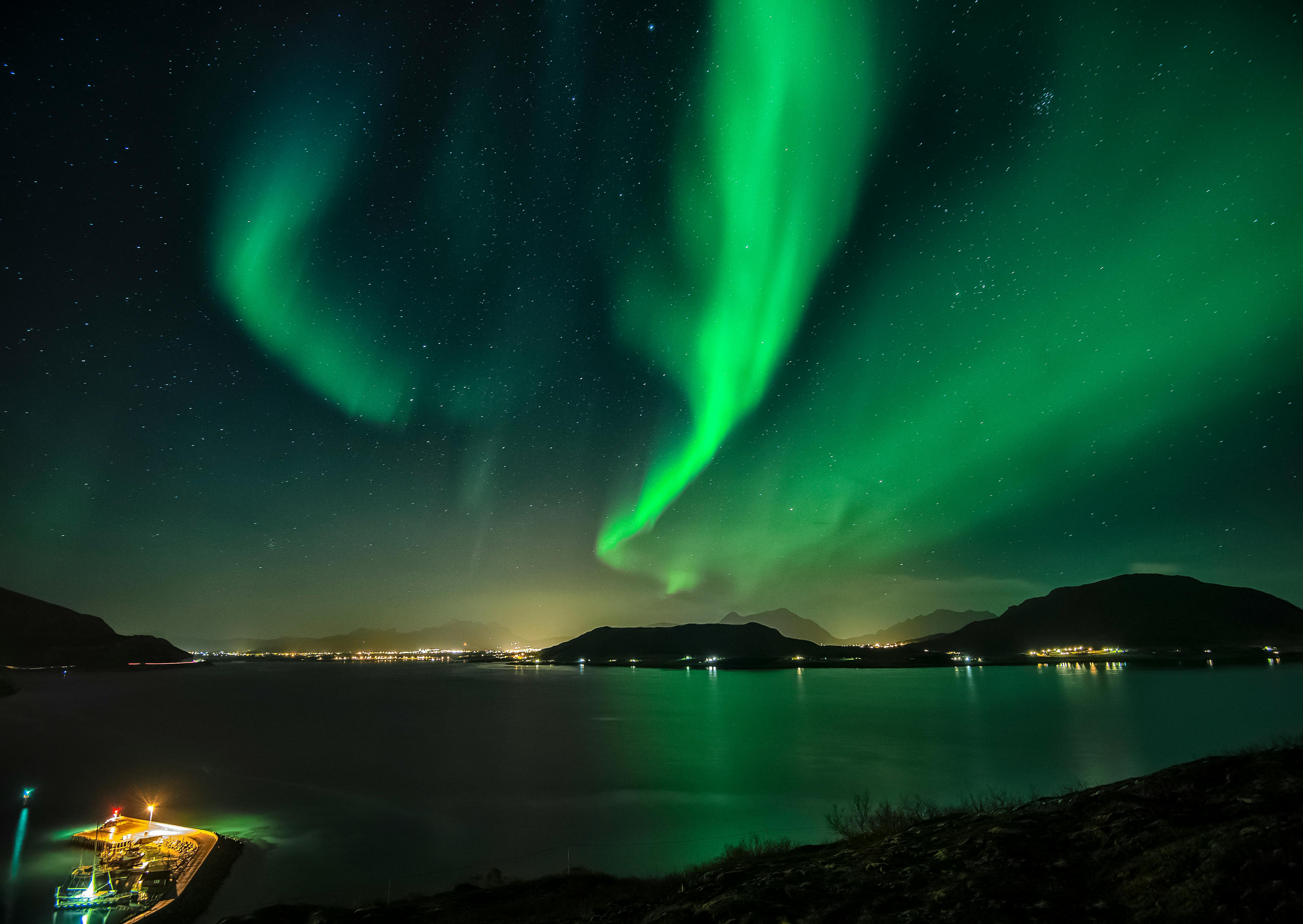 Mesmerizing view of Northern Lights above a serene Norwegian fjord during a starry night.