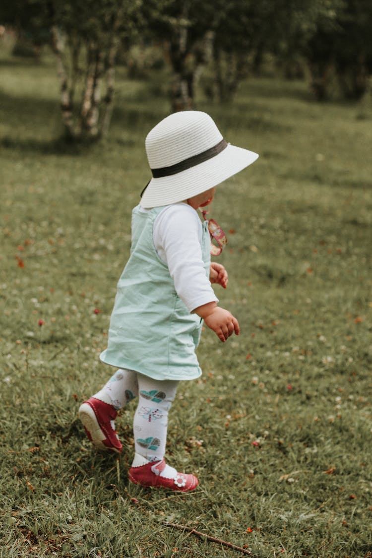 A Toddler Walking On Grass