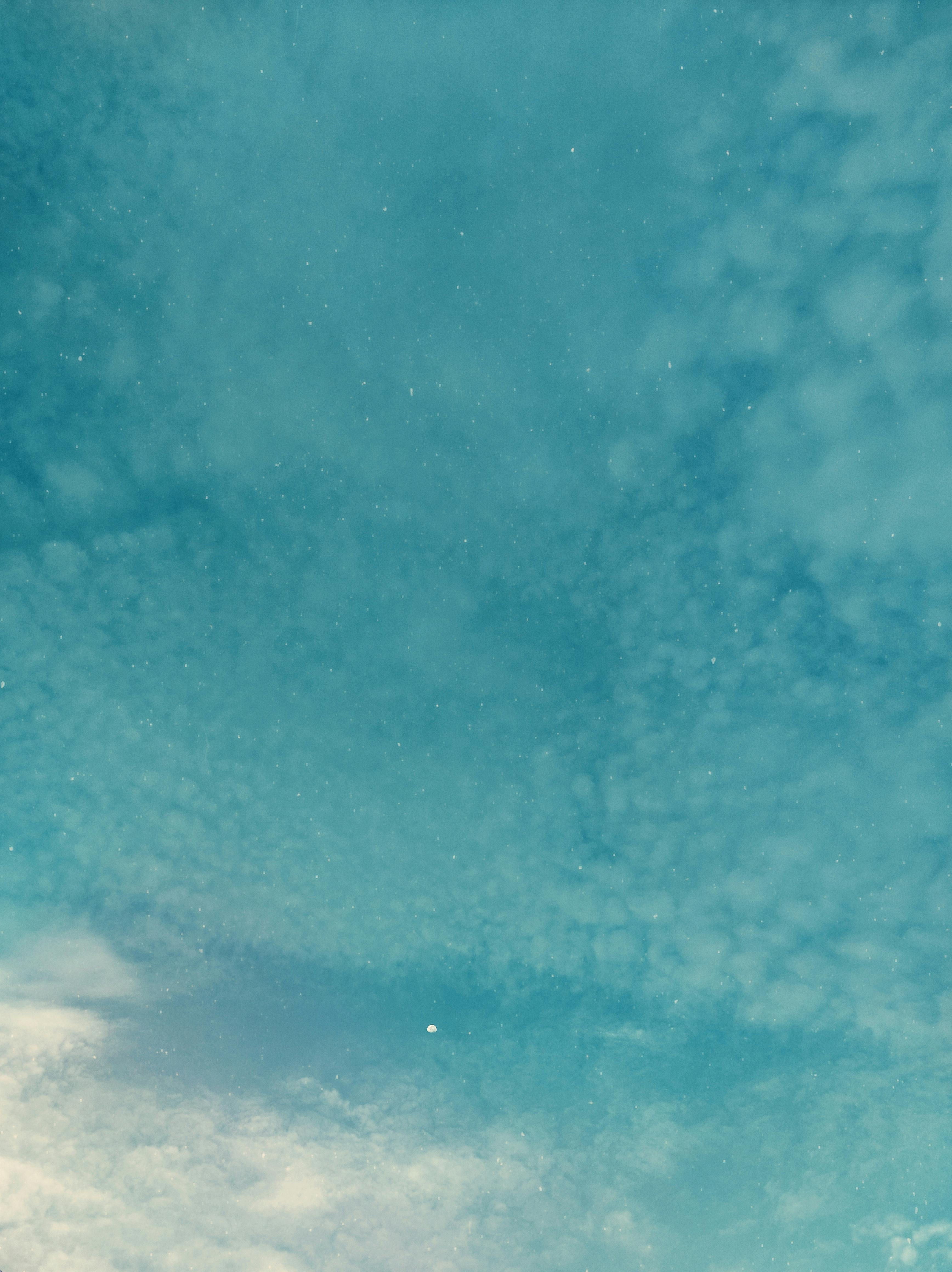Serene view of a blue sky with scattered clouds and a faint moon, perfect for dreamy backgrounds.