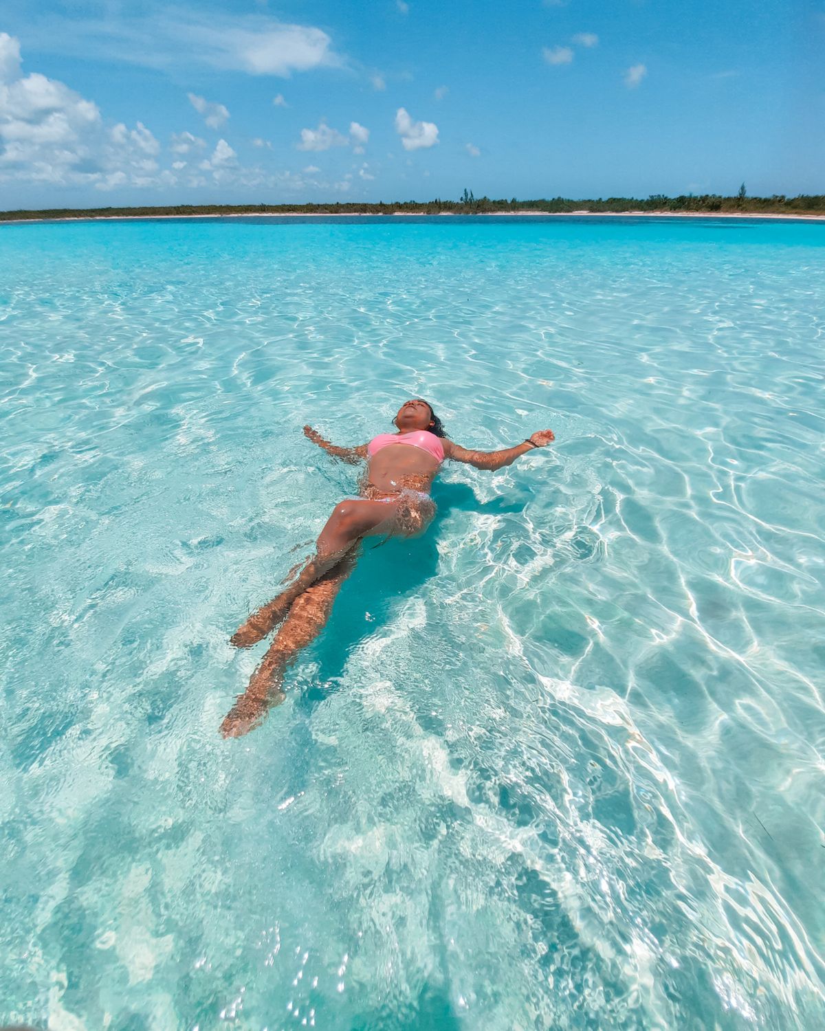 A woman floating in swimsuit in the bright turquoise waters of San Miguel de Cozumel.