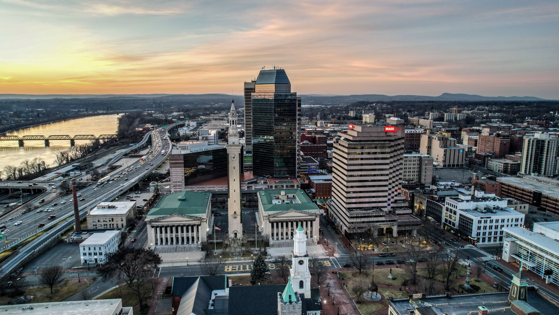 Discover a vibrant cityscape with modern architecture and a river at sunset.