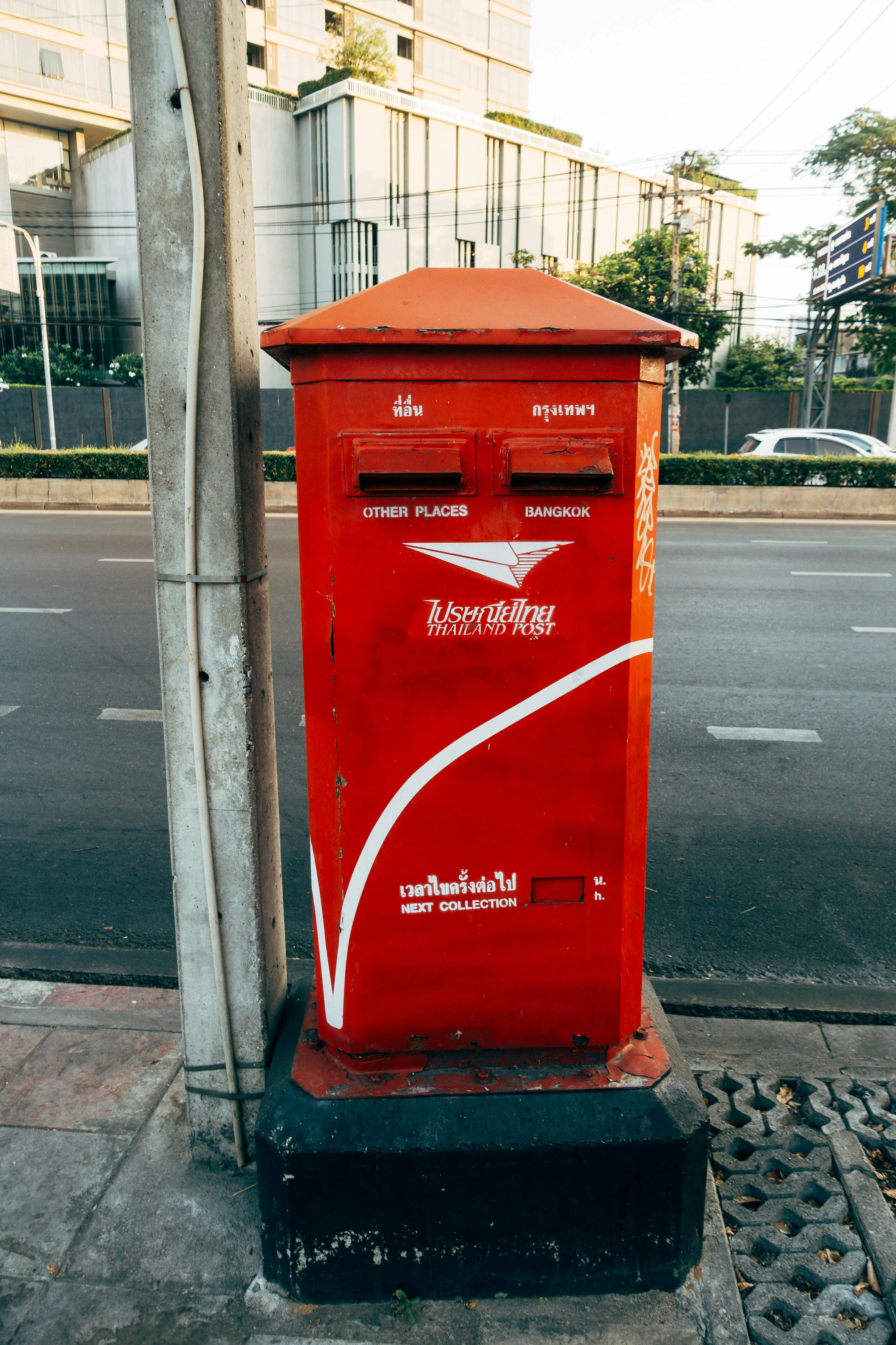 red mail box on gray asphalt road