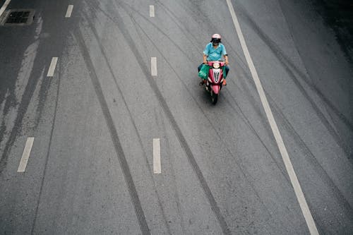 Person in Blue Shirt Riding Motorcycle on the Road