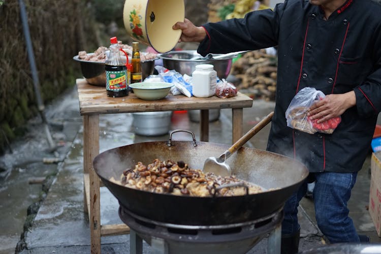 Person Cooking Mushrooms In A Wok