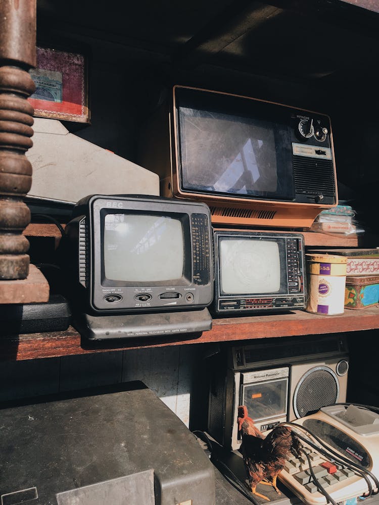 Vintage Televisions And A Radio On Wooden Shelves