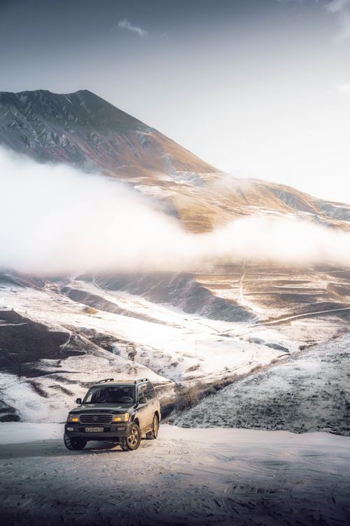 Free SUV exploring scenic snow-covered mountains under a clear sky. Stock Photo