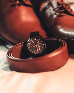 Stylish close-up of brown leather shoes, belt, and wristwatch for fashion-forward men.
