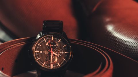 Close-up of a stylish men's wristwatch with leather shoes and belt, highlighting elegance and fashion.