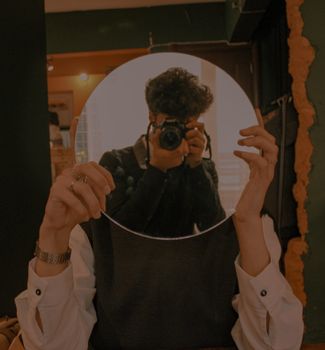 Artistic composition featuring a person capturing their reflection in a round mirror.