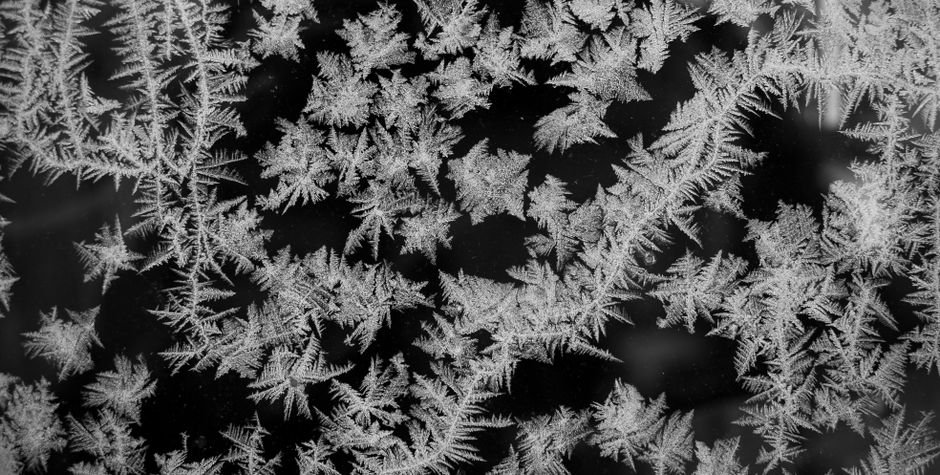 Close-up of intricate frost patterns on a window, showcasing natural icy designs in winter.