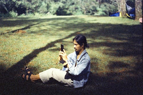 A Man Using his Cellphone while Sitting in a Park